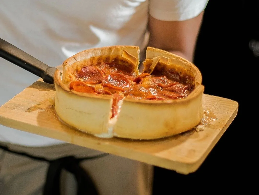 Pizza de pepperoni estilo Chicago sobre una tabla de madera, de la carta de Vulcanos.